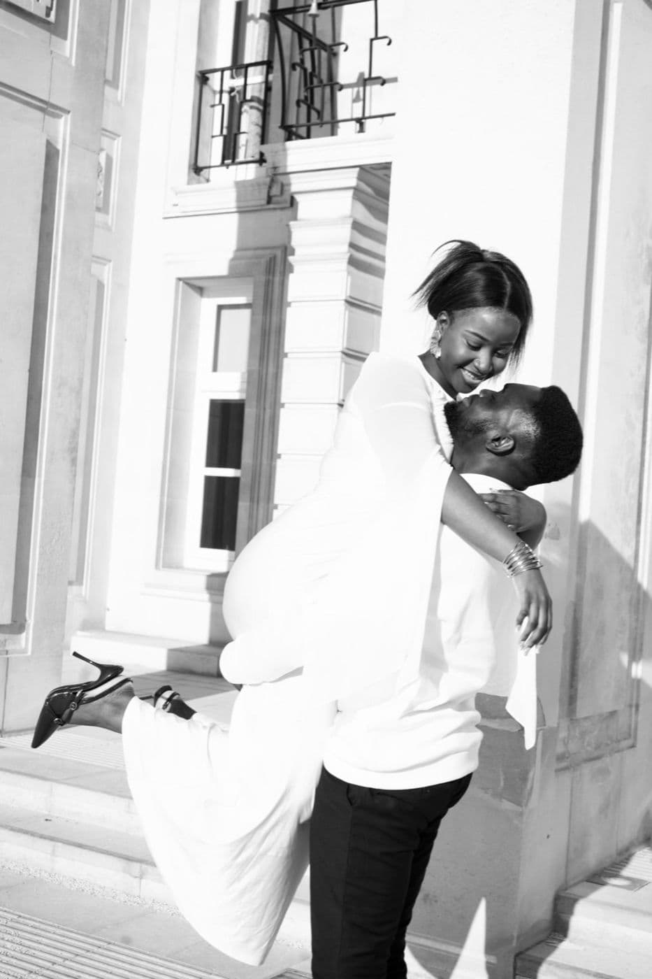 Black and white. A couple embracing, a long veil lifted behind them.