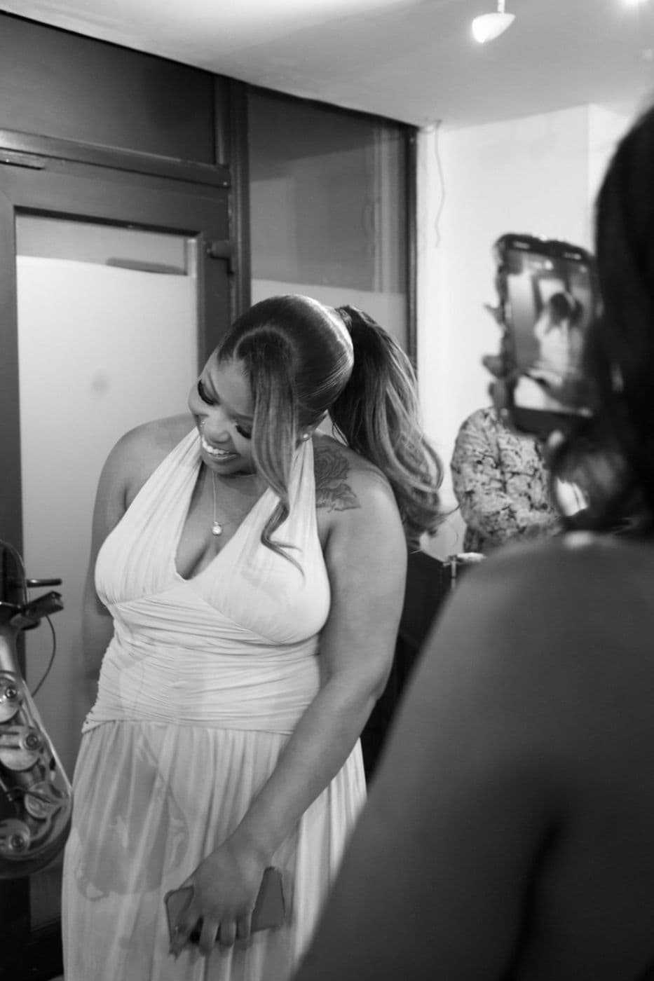 Black and white. A woman in a light dress laughing, her head tilted.