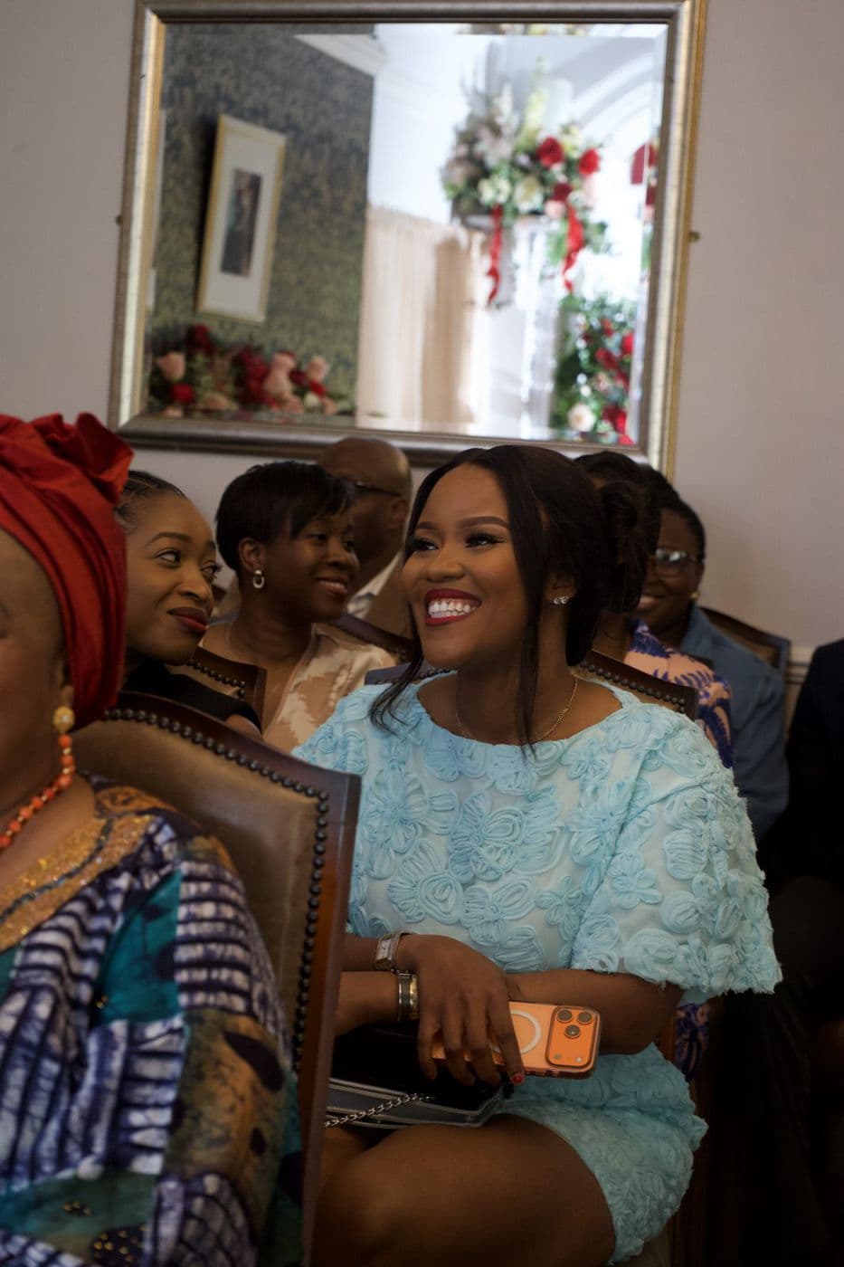 A group seated indoors laughing together, one woman in pale blue.